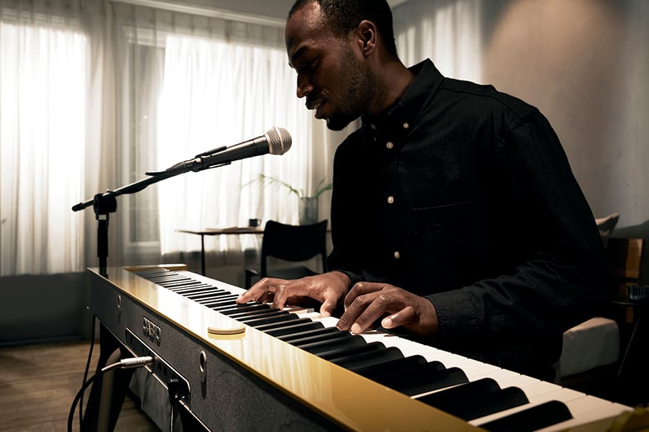 Male musician playing a yellow PX-S7000 keyboard with microphone plugged into the back port