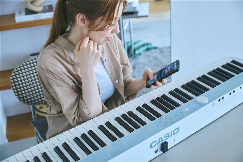 Imagen de una persona manipulando su teléfono inteligente cerca del piano
