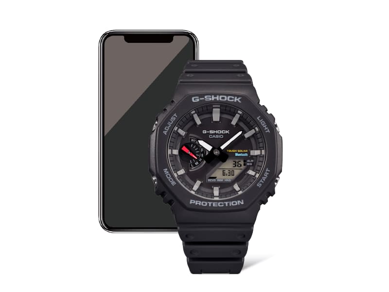 Delante: un reloj de pulsera Casio G-Shock GA-B2100 negro, detrás: un smartphone negro