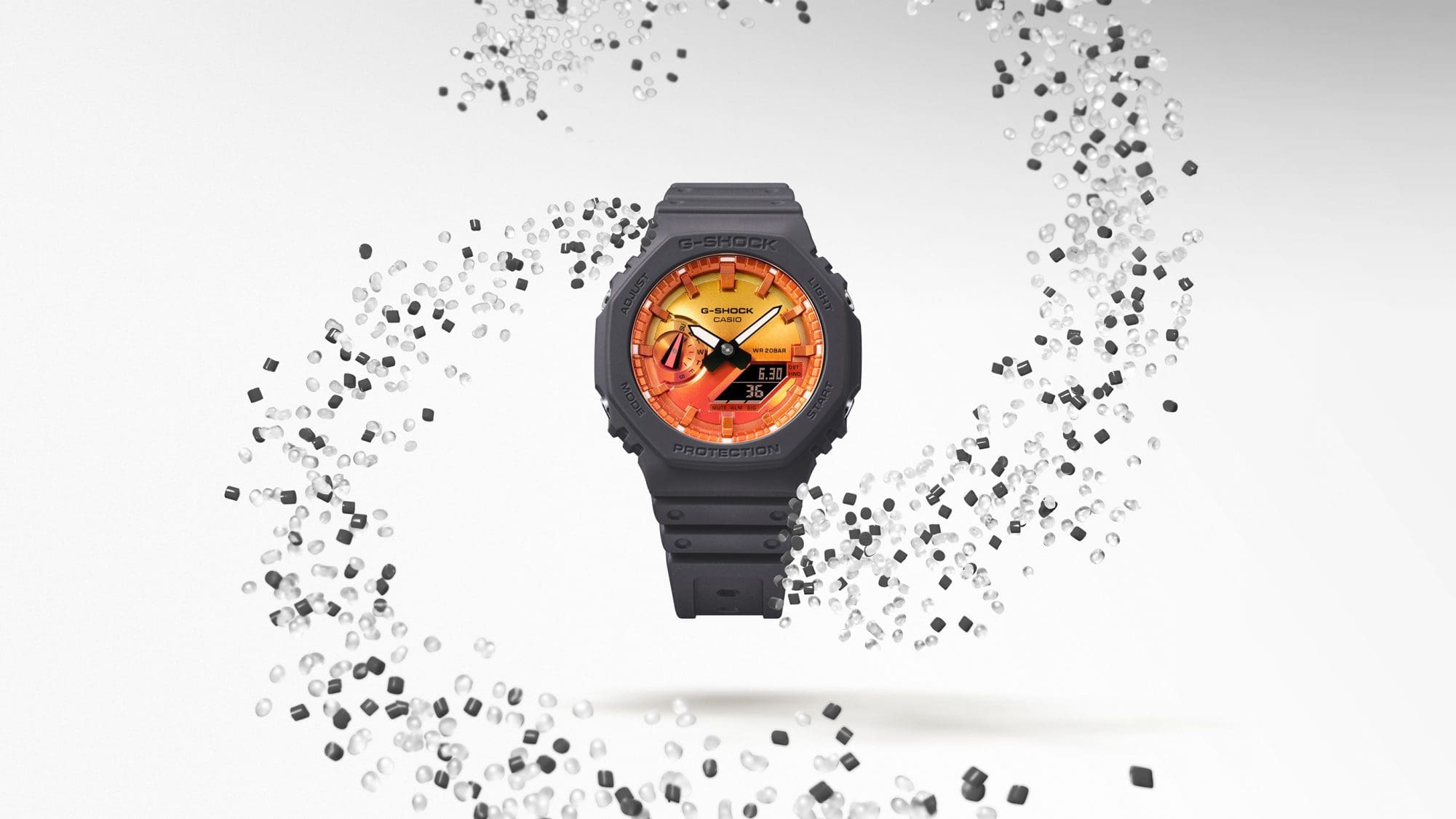 El reloj híbrido GA-2100FL-8A rodeado por un remolino de granulado de resina transparente y gris