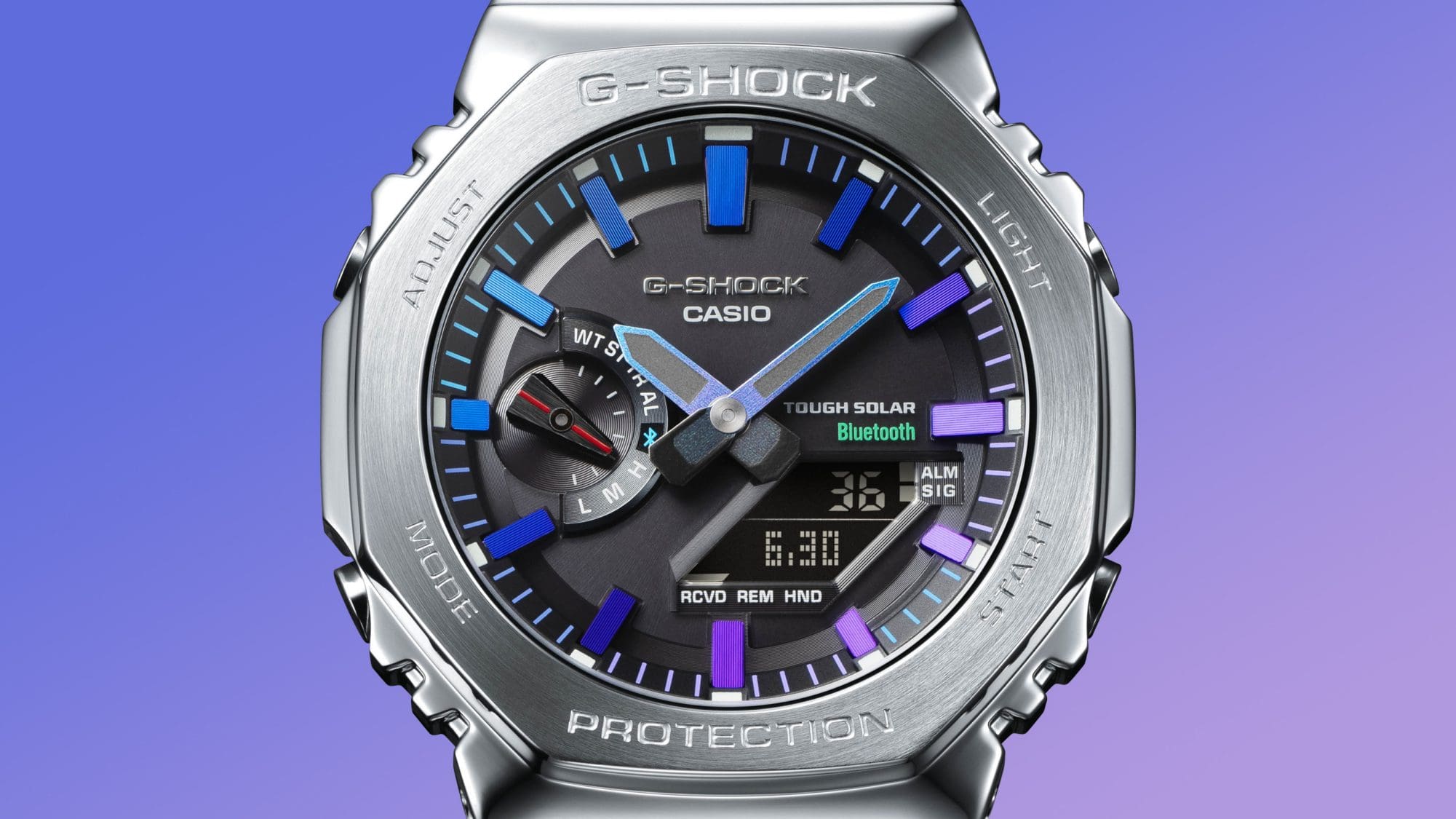 Detalle de la esfera negra del reloj de pulsera Casio G-Shock GM-B2100PC con marcas de índice en varios tonos de azul y morado