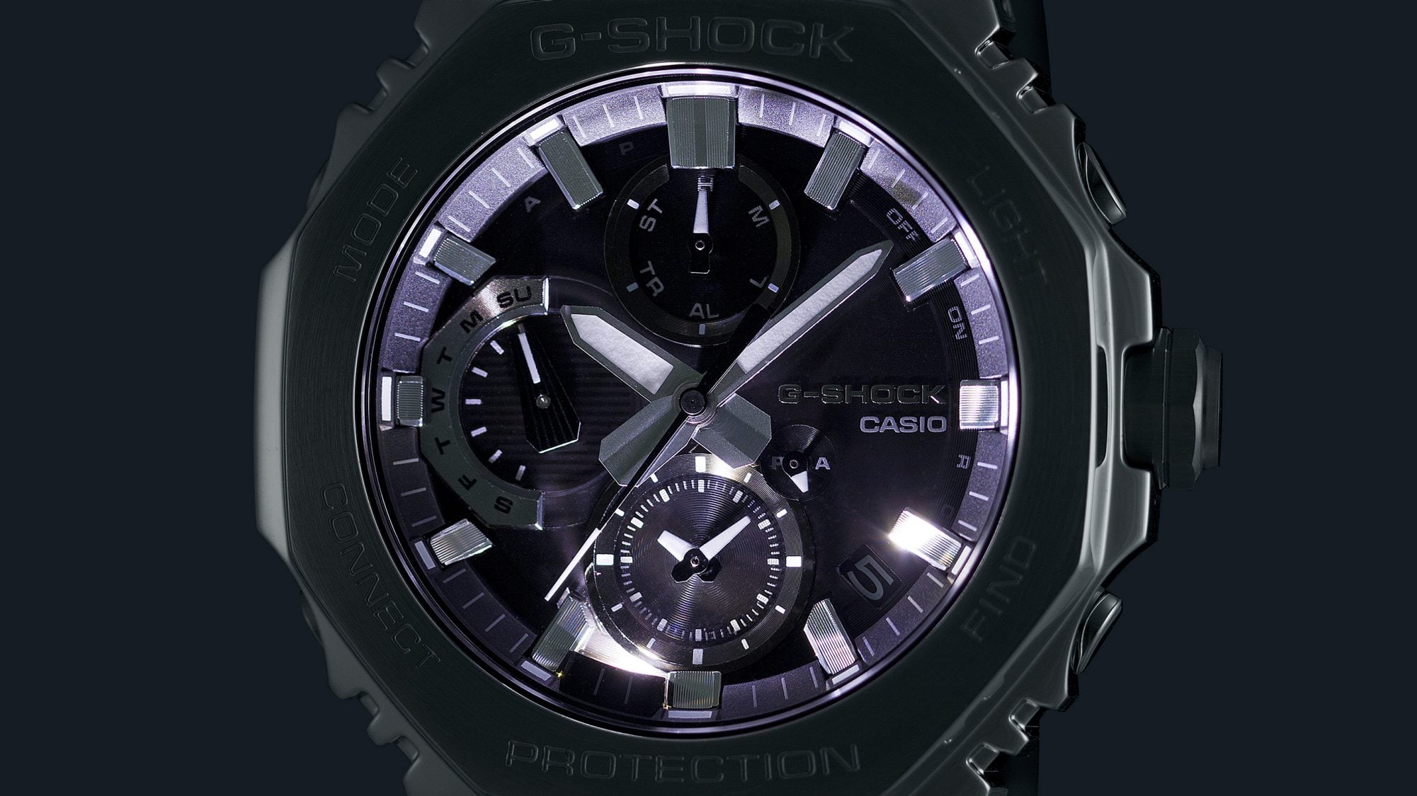 La pantalla de un cronógrafo Casio G-Shock GMC-B2100 en la oscuridad con la esfera iluminada.