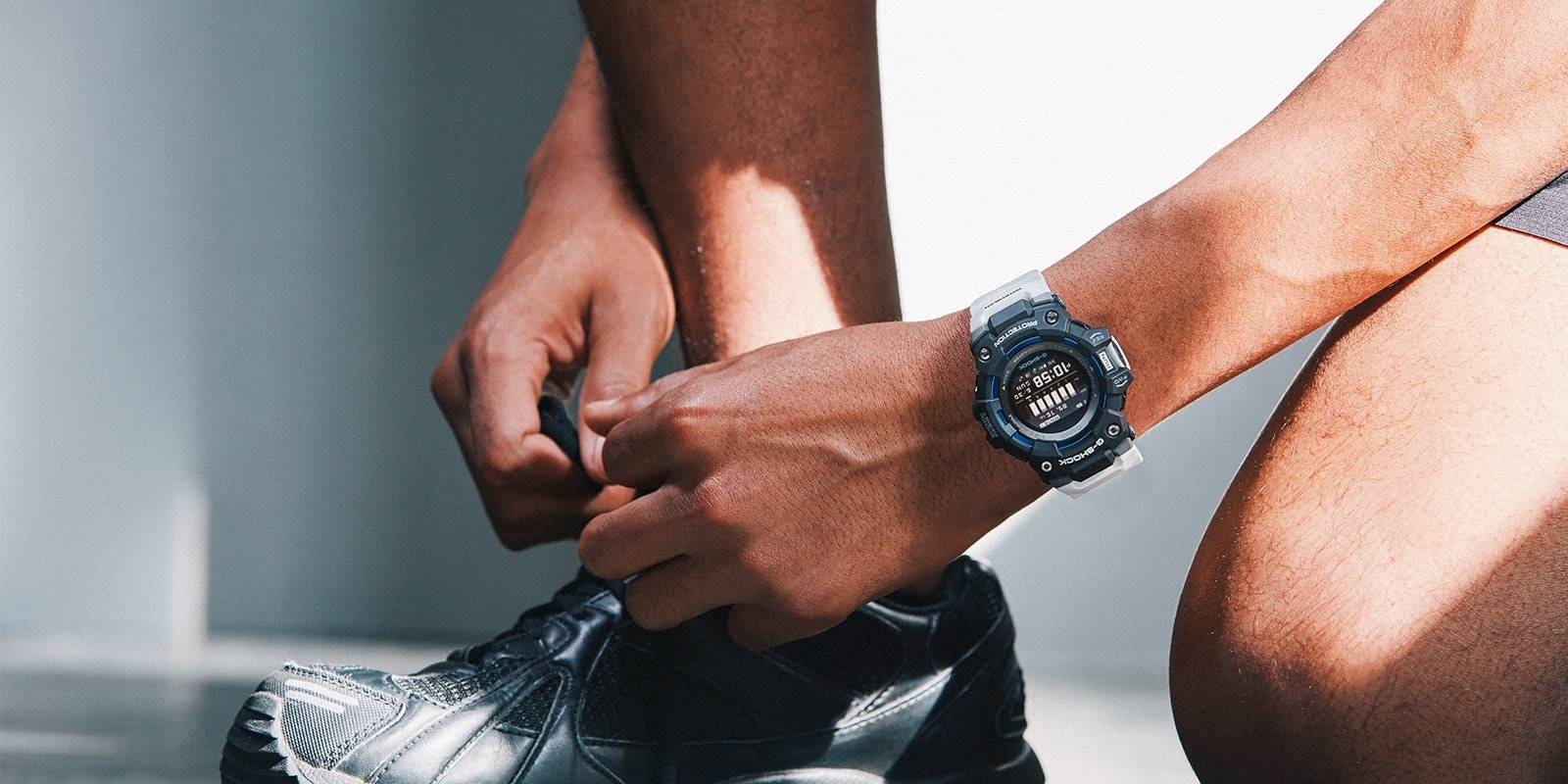Alguien se ata los cordones de sus zapatillas de correr y lleva en el brazo el reloj Casio G-Squad GBD-100-1A7