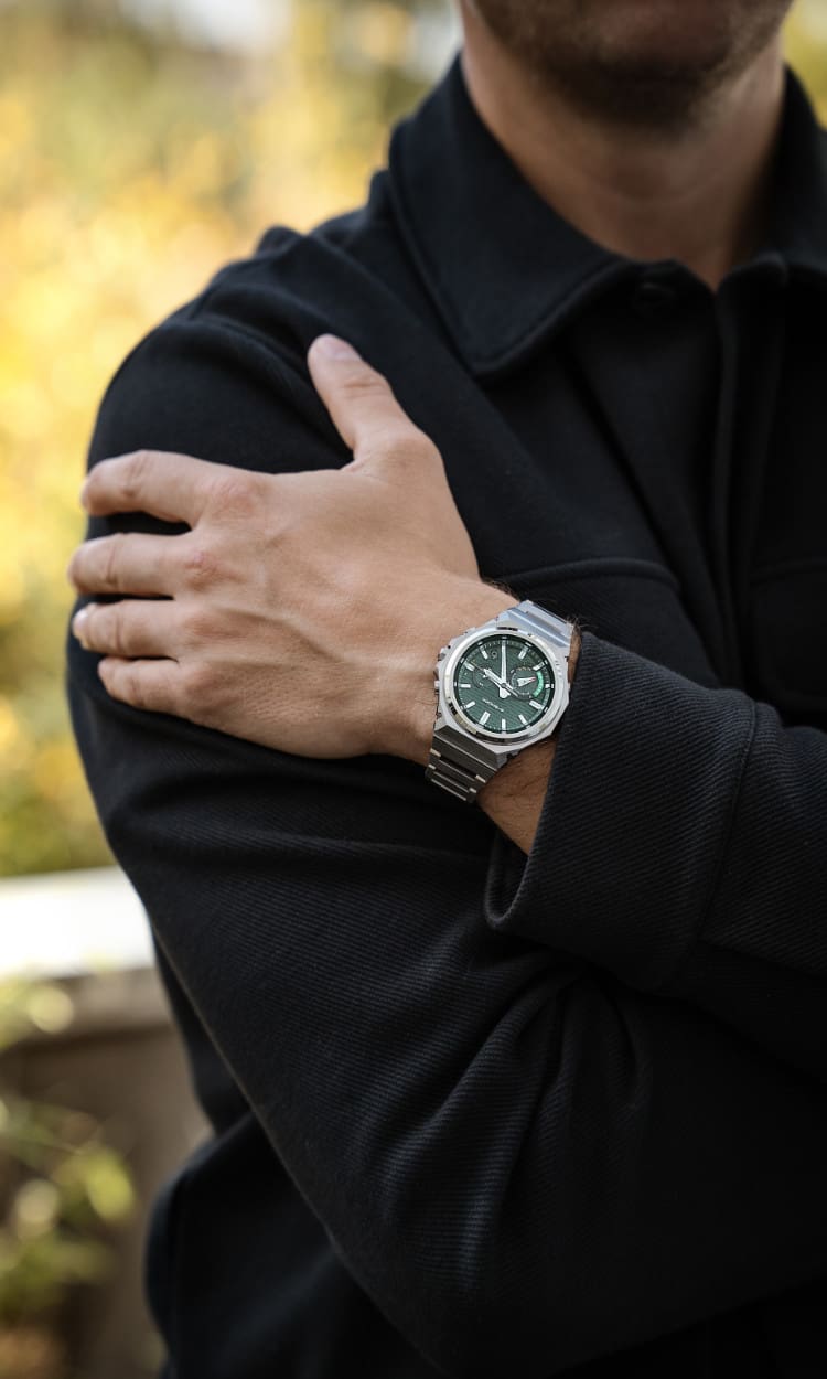 Plano medio de un hombre con camisa negra que lleva el reloj de pulsera GST-B1000 con esfera analógica verde oscuro.