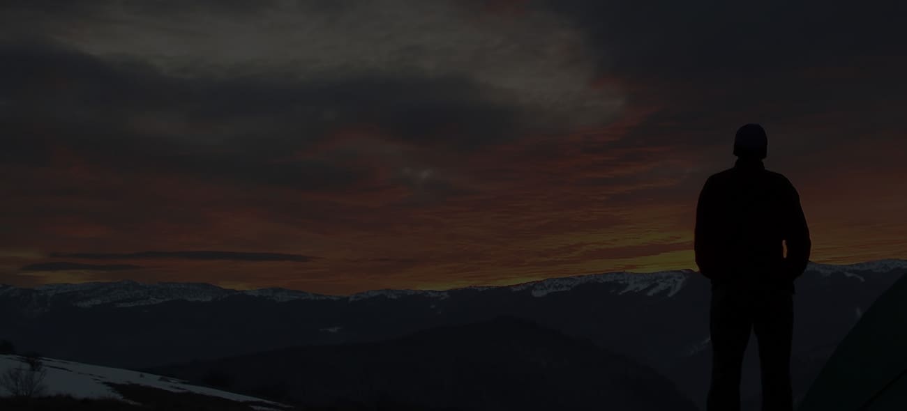 Silueta de un hombre en una montaña mirando la puesta de sol