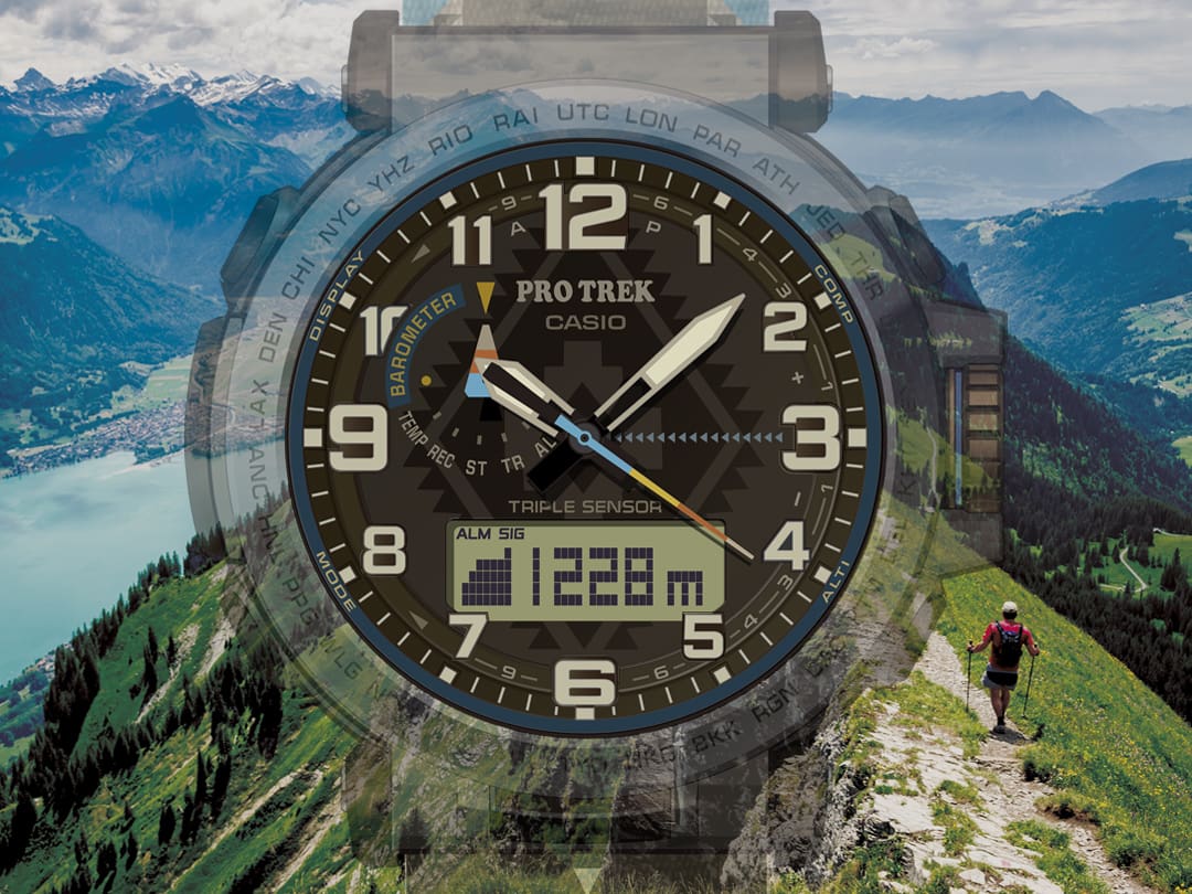 La pantalla digital del reloj para alpinistas PRG-601PE-5 muestra datos de altitud, mientras que en el fondo se ve a alguien caminando por una cresta verde.