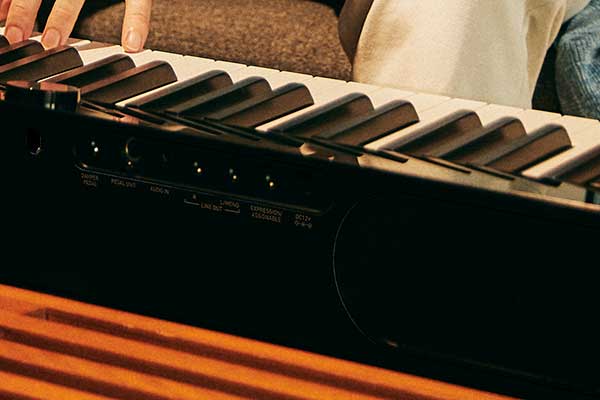Primer plano de la parte trasera del piano digital Privia PX-S3100BK negro con altavoces y tomas de conexión