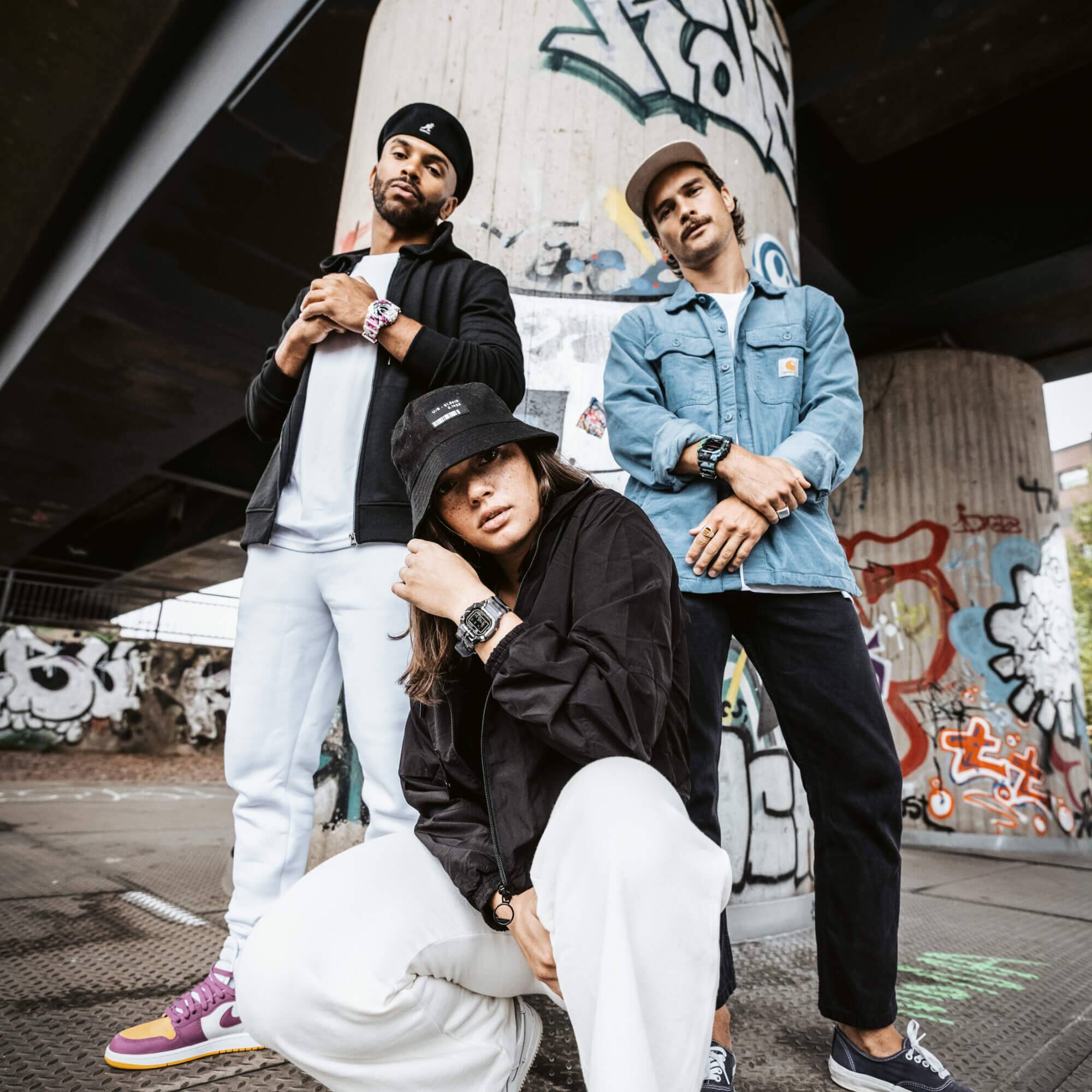 Fotografiado desde la perspectiva de la rana: Tres personas bajo un puente con grafitis y con diferentes modelos de G-SHOCK.