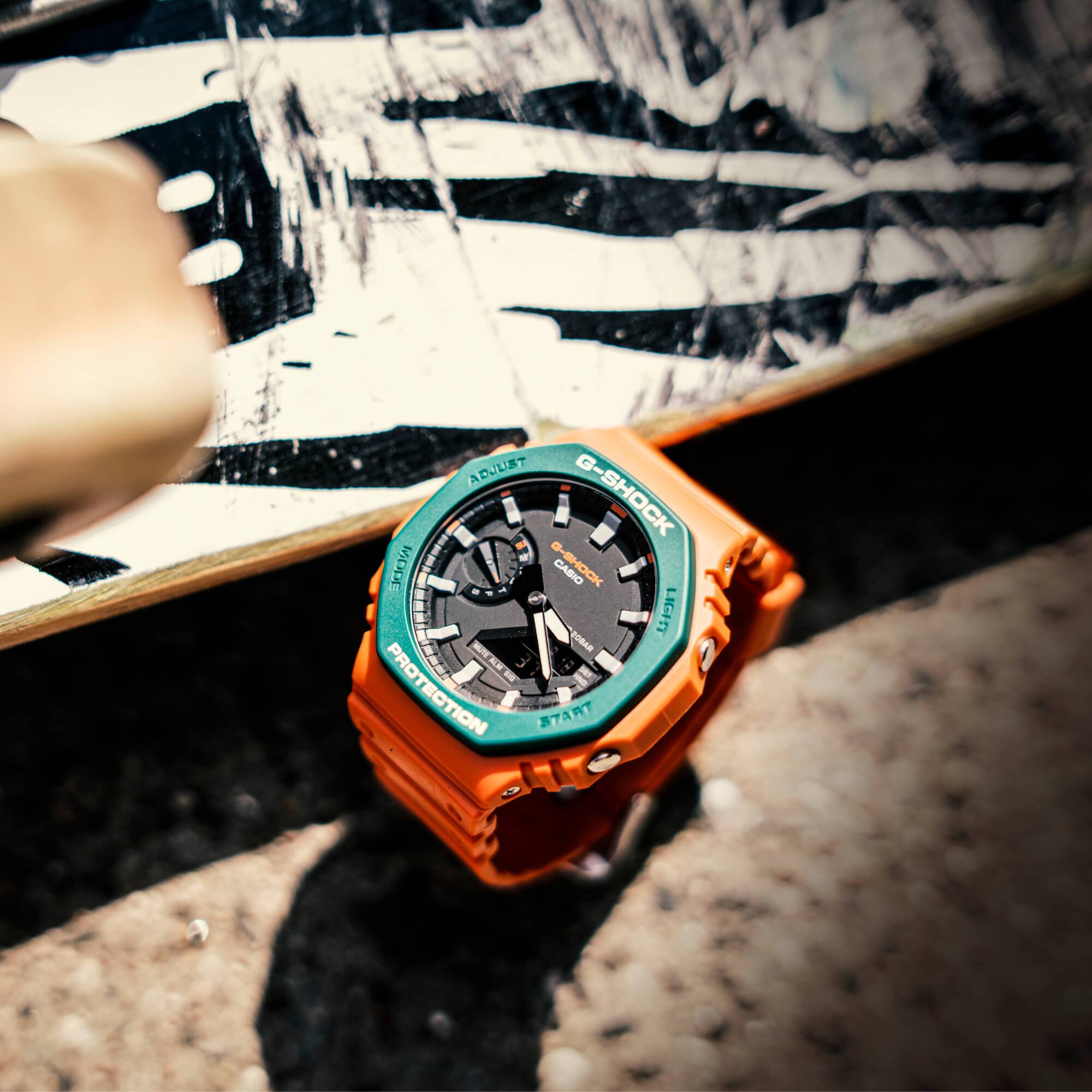 G-SHOCK GA-2110SC-4A tirado en el suelo junto a un monopatín.