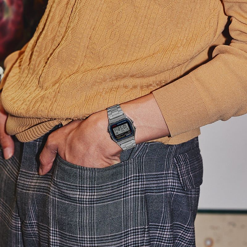 La montre numérique argentée A158 au poignet d'une personne portant un pull marron.