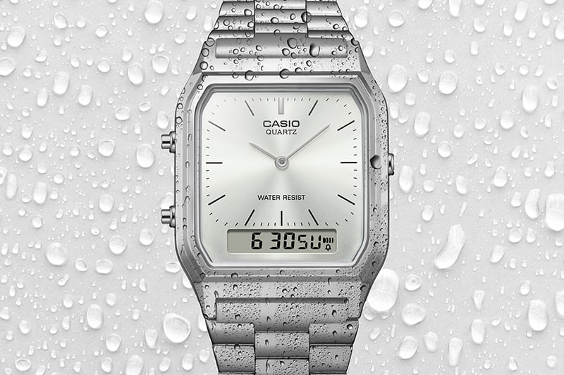 La montre analogique AQ-230 avec des gouttes d'eau sur l'écran, afin de démontrer son étanchéité