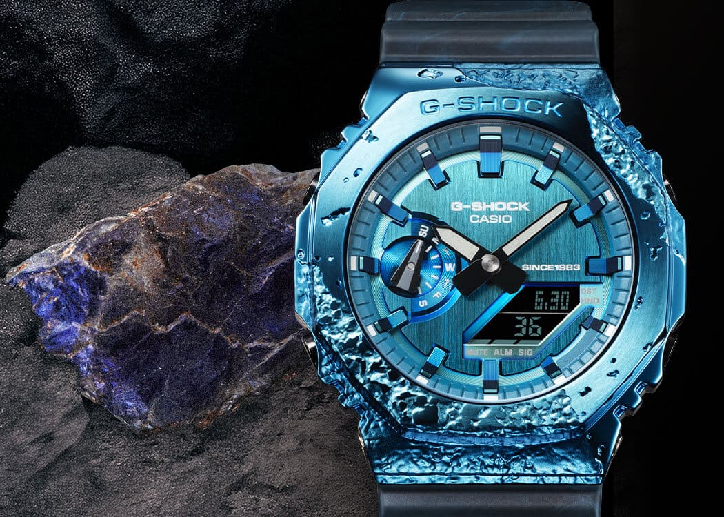 La montre anniversaire GM-2140GEM-2A, d'un bleu éclatant, à côté d'une pierre cordiérite bleutée