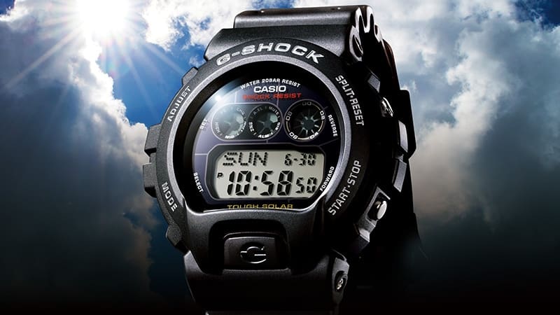La montre solaire noire Casio G-Shock GW-6900-1 sur fond de ciel nuageux traversé par un rayon de soleil.