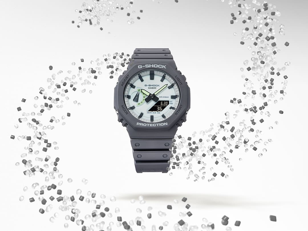 La montre hybride GA-2100HD-8A entourée d'un tourbillon de granulés de résine transparente et grise
