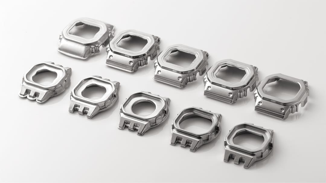 Dix lunettes de couleur argentée à différents stades de fabrication - de l'ébauche à la lunette finie de la montre solaire Casio G-Shock GMW-B5000SS-2.
