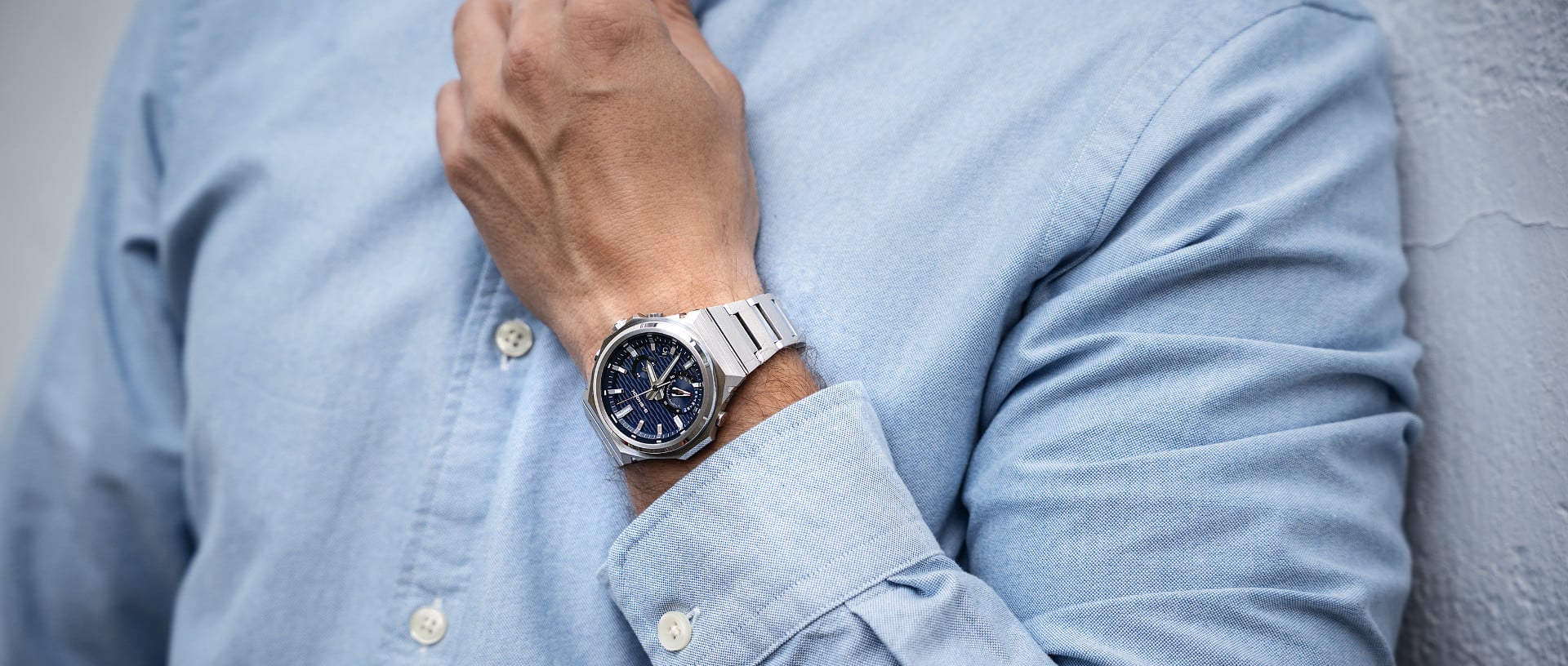 Un homme vêtu d'une chemise bleu clair porte la montre G-SHOCK GST-B1000 avec un cadran bleu foncé à son poignet.