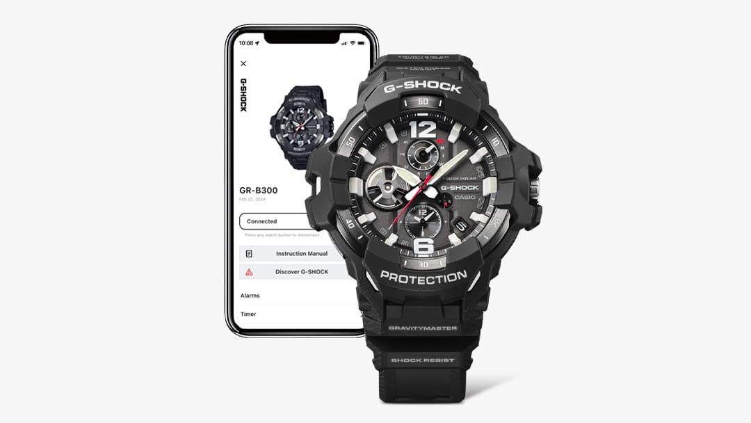 Une montre Master of G GR-B300 Bluetooth® noire devant un smartphone dont l'écran affiche des informations sur la montre.
