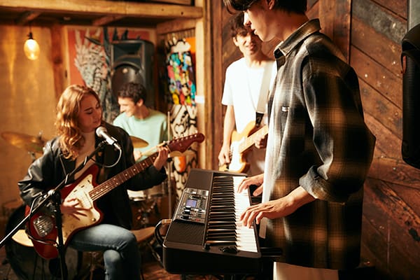 Un groupe de quatre jeunes gens joue dans un pub rustique, le claviériste joue sur le piano numérique Casiotone CT-S500