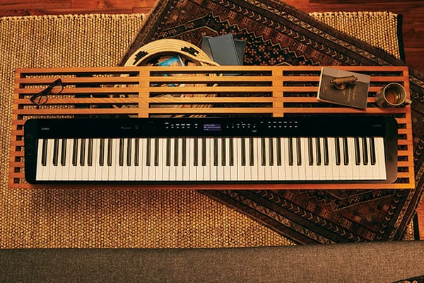 Vue d'en haut d'une table de salon en bois et du piano numérique Privia PX-S3100BK