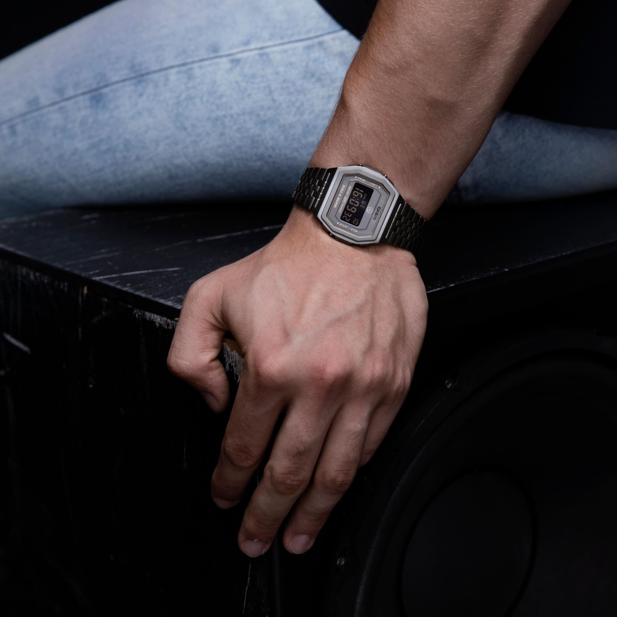 Une personne s'appuie sur une table et porte la montre Casio Vintage A1000RCG-8A.