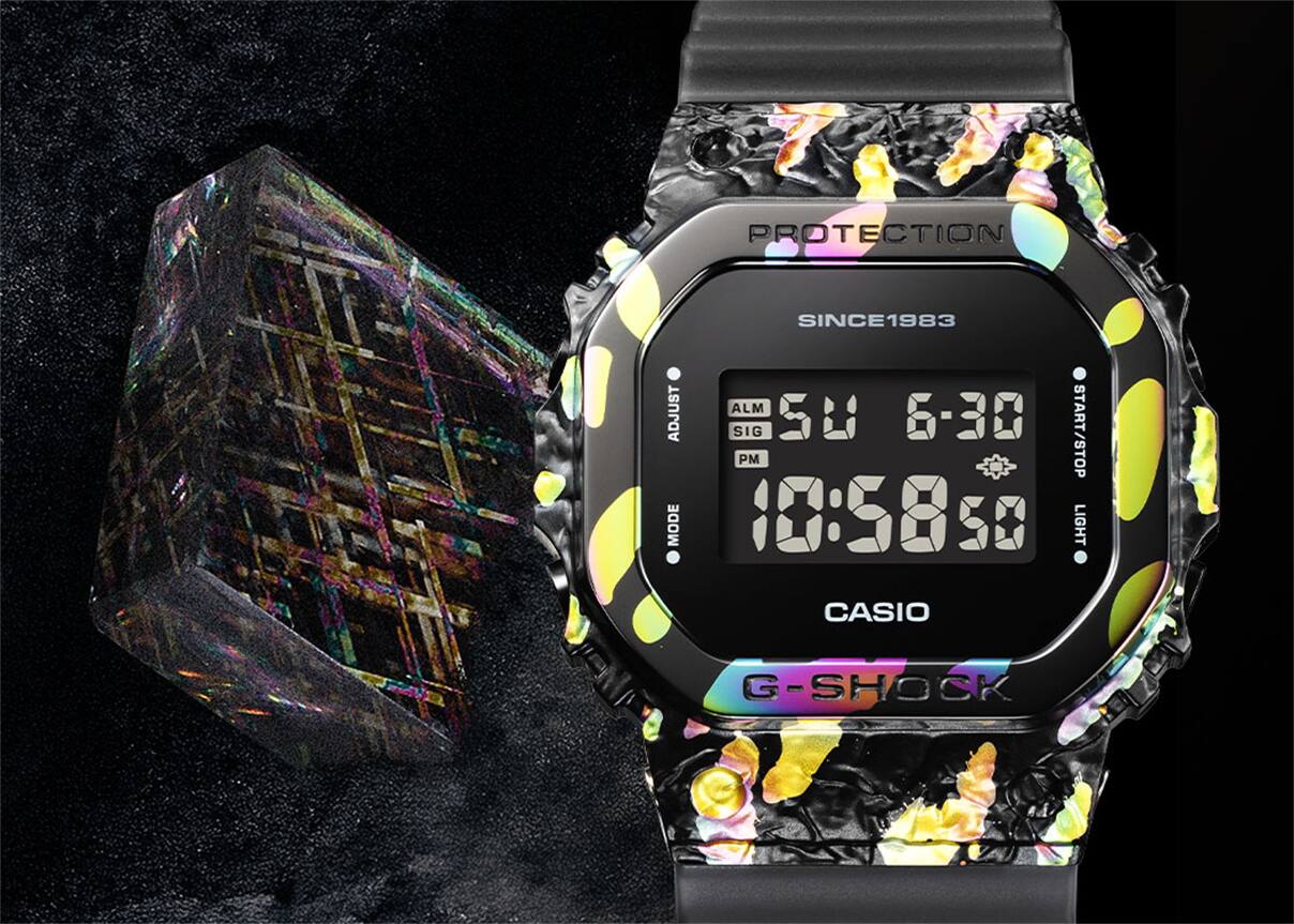 GM-5640GEM-1 L'orologio GM-5640GEM-1 Anniversary accanto a un blocco trasparente attraversato da linee dai colori dell'arcobaleno