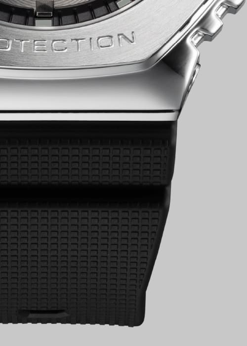 Primo piano della transizione tra la cassa in acciaio inossidabile color argento e il cinturino nero testurizzato dell'orologio da polso Casio G-Shock GM-2100-1A