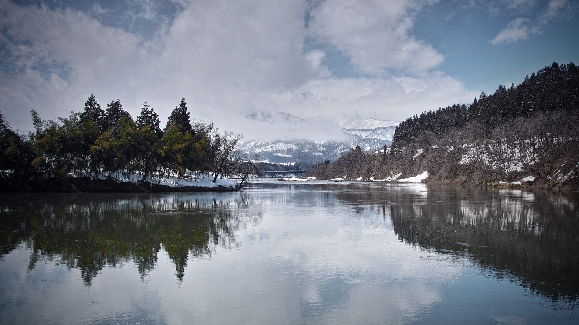 Un lago limpido circondato da montagne e da una foresta