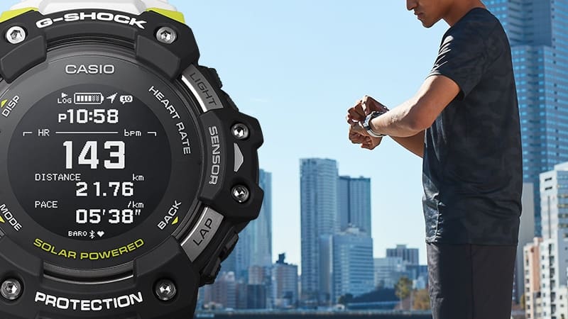 Un uomo in piedi davanti allo skyline di un grattacielo guarda l'orologio