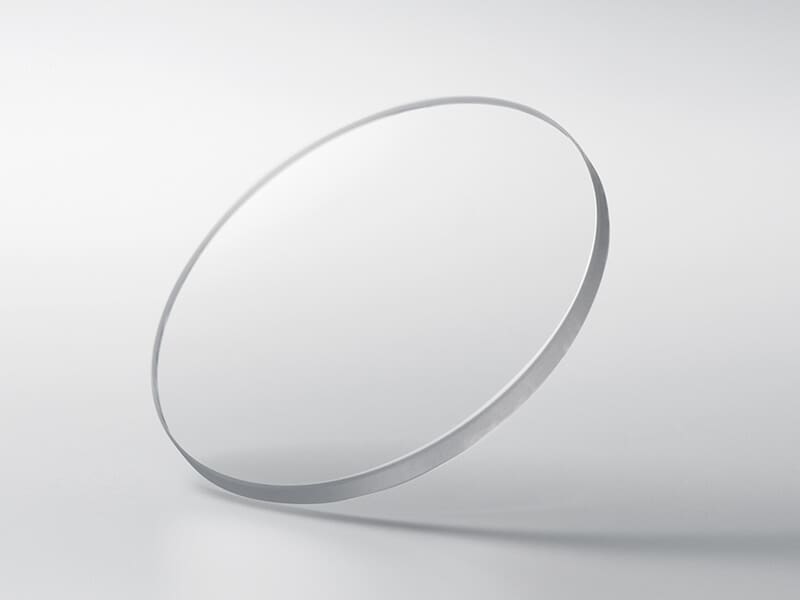Un disco rotondo in vetro zaffiro su uno sfondo grigio chiaro