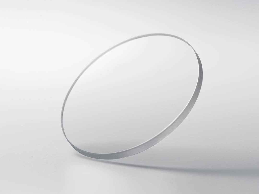 Un disco rotondo in vetro zaffiro su uno sfondo grigio chiaro
