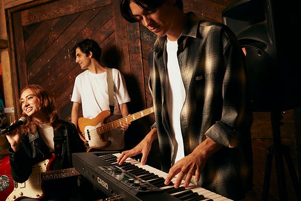 Un tastierista suona al pianoforte digitale Casiotone CT-S500 insieme a un cantante e a un chitarrista