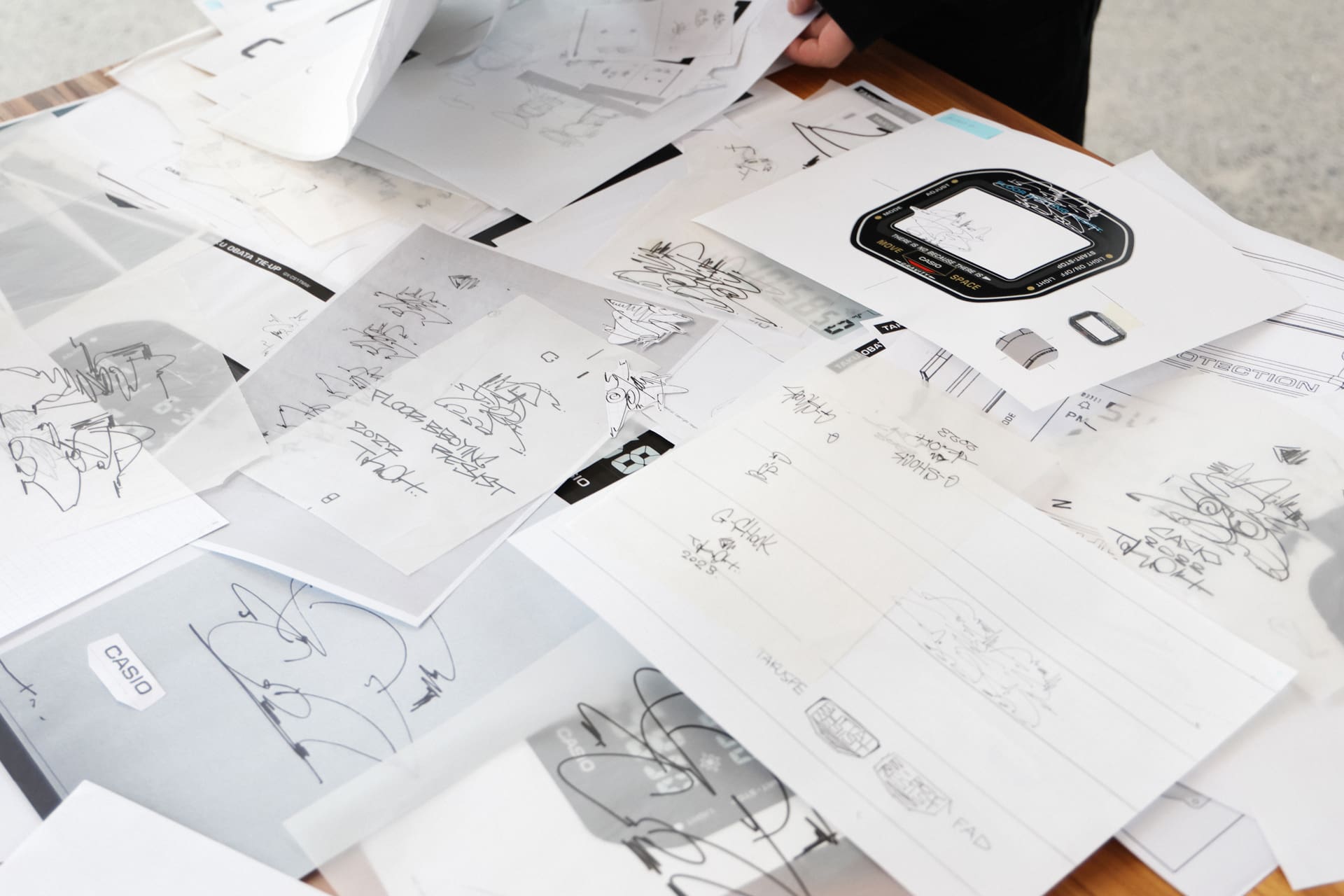 膨大な量のデザイン制作過程。実際に作品をドローイングして、時計を大判サイズにした平面上で、切って貼ってどこに配置するかデザインを整えていったそう