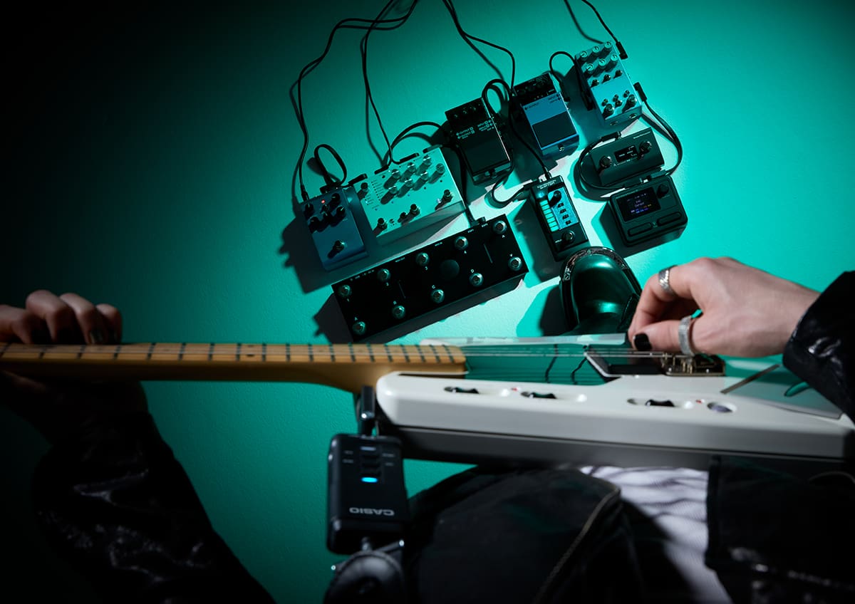 ギタリストの視点でDIMENSION SHIFTERを装着したギターを弾いている写真。足元には、複数のエフェクターが連結されている。