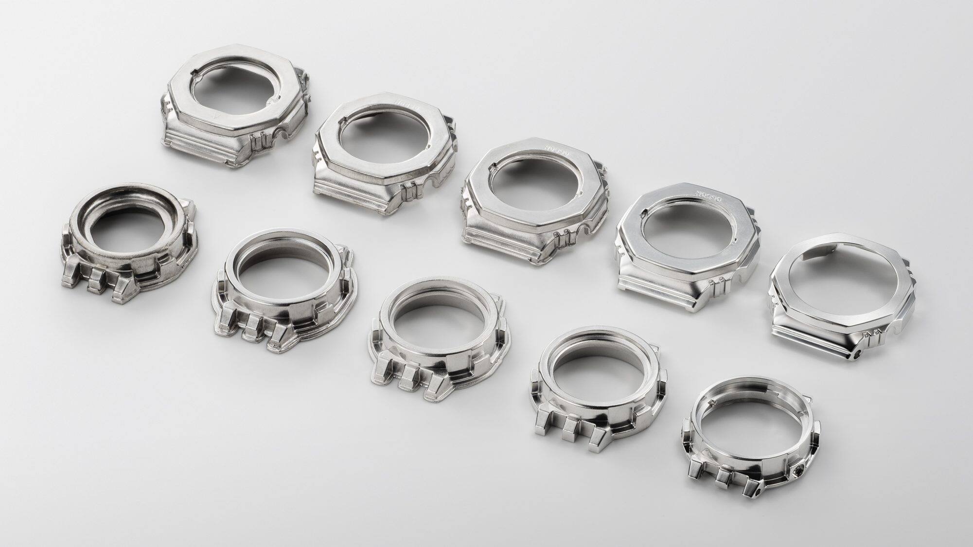 Tien zilverkleurige bezels in verschillende stadia van productie - van de lege tot de afgewerkte bezel van het Casio G-Shock GM-B2100AD hybride horloge