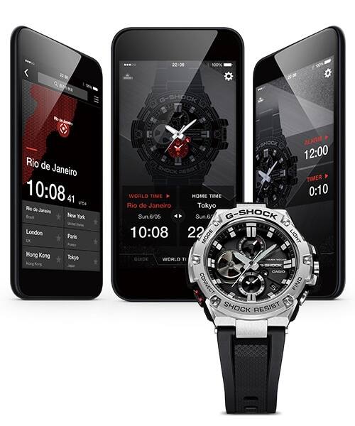 Drie smartphones met verschillende G-Shock Connected app schermen, voor een Casio G-Steel GST-B100 polshorloge met zwarte band en wijzerplaat en zilverkleurige roestvrijstalen kast.