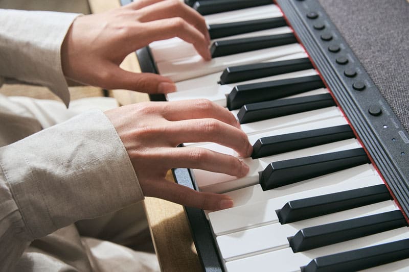 Close-up van twee handen die de piano en het toetsenbord van de Casiotone CT-S1-76 digitale piano bespelen