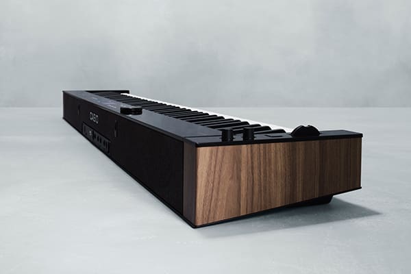 Zicht op een hoek van de PX-S6000 digitale piano, waar de glanzend zwarte lange zijde en de smalle zijde met walnoot houtnerf elkaar ontmoeten