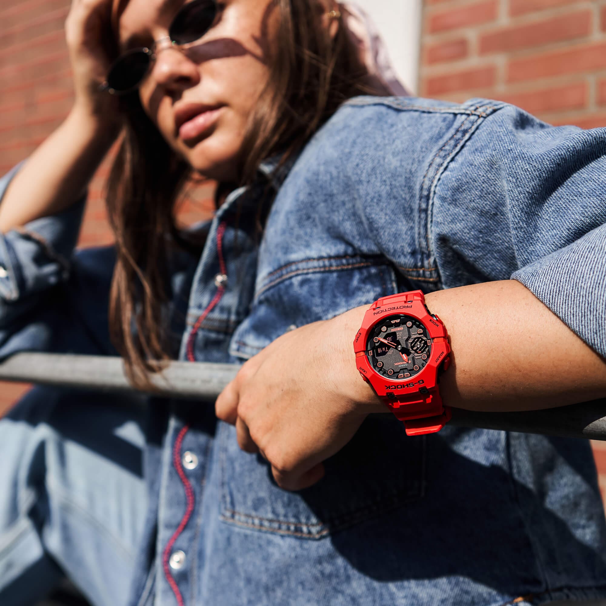 Een vrouw draagt het rode G-SHOCK horloge "GA-B001-4AER".