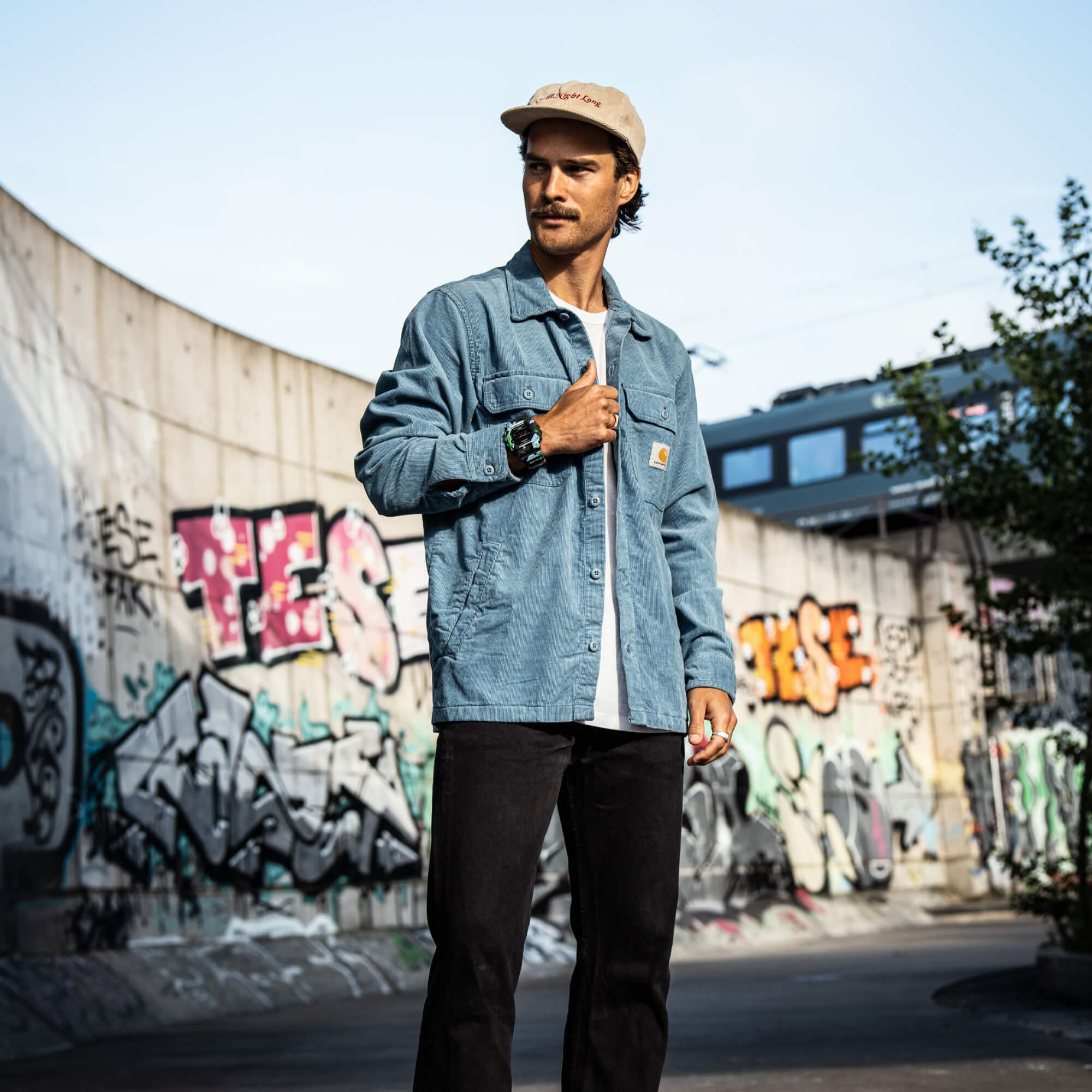Een man met pet en denim shirt draagt het GX-56SS-1ER polshorloge van G-SHOCK om zijn pols.