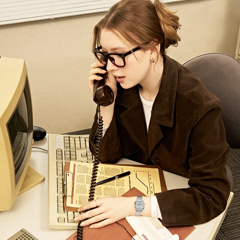 Imagem de uma mulher usando um relógio LA680 prateado e falando ao telefone.