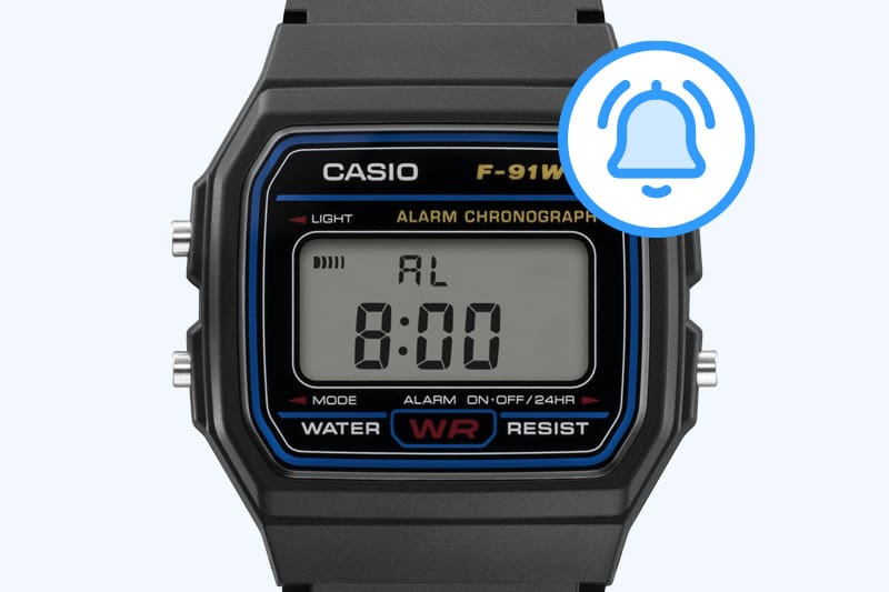 Um ícone de alarme azul ao lado do visor do relógio de pulso digital preto