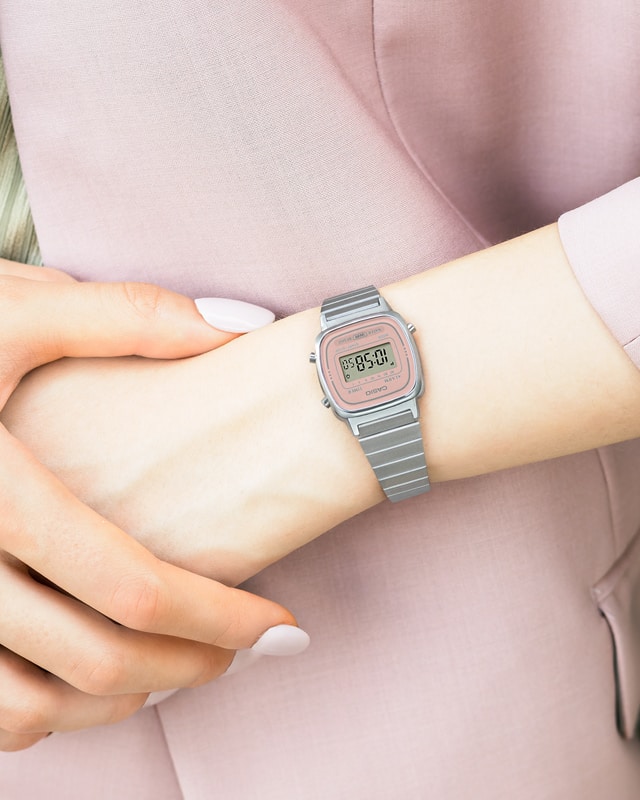 LA670WEA-4A2 O relógio digital estreito LA670WEA-4A2 da coleção mini da Casio Vintage Collection com bracelete em aço inoxidável prateado e moldura do ecrã rosa num pulso feminino fino