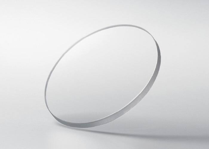 Um disco redondo em vidro de safira sobre um fundo cinzento