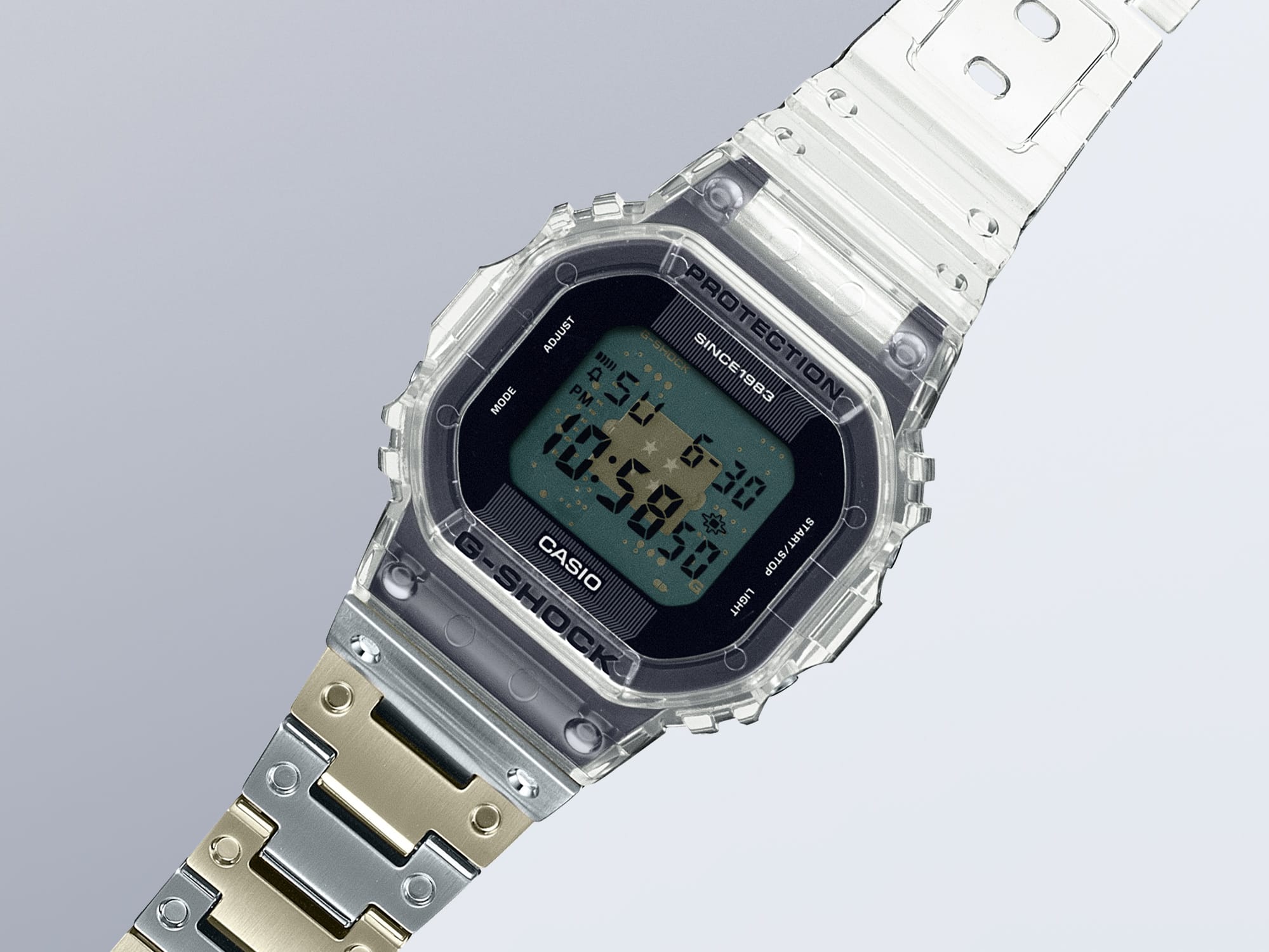 O relógio de aniversário G-Shock DWE-5640RX-7 com o seu elemento de bracelete transparente na posição das 12 horas e a sua bracelete em aço inoxidável dourado e prateado na posição das 6 horas