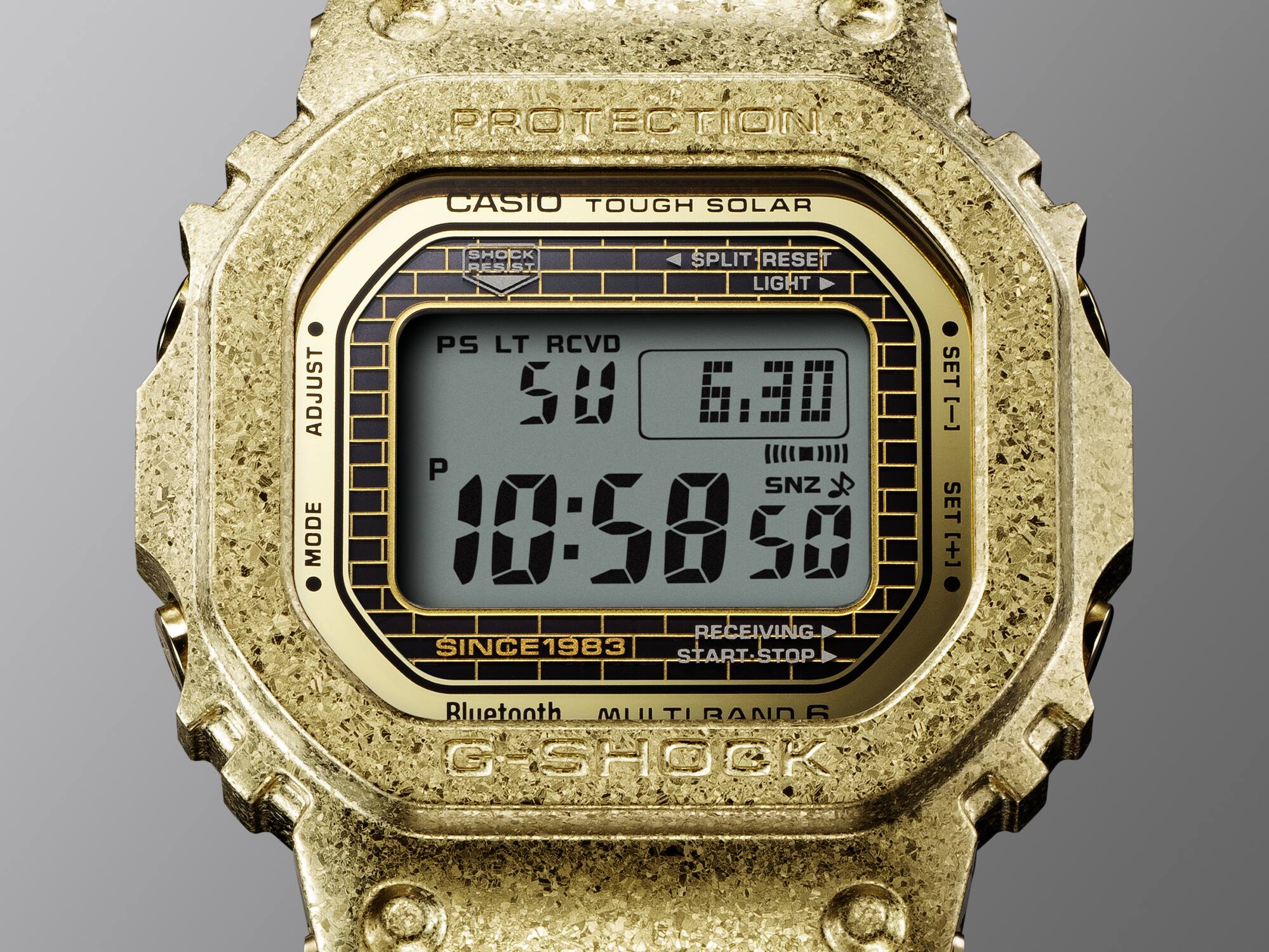 Grande plano do mostrador do relógio de aniversário Casio G-Shock GMW-B5000PG-9 com padrão de tijolo e moldura dourada