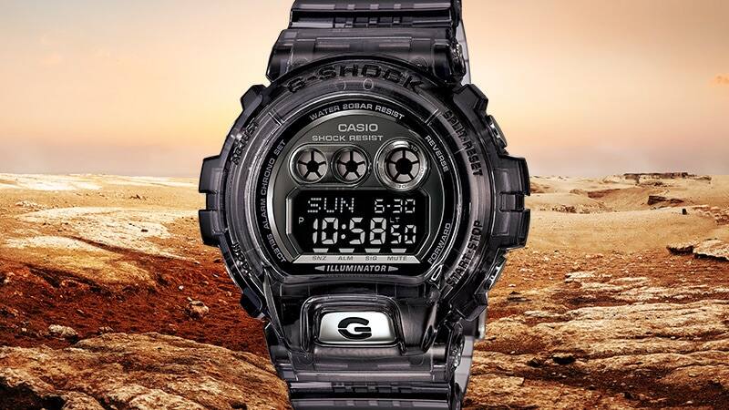 O relógio digital Casio G-Shock GD-X6900FB-8B preto em frente a uma paisagem rochosa árida