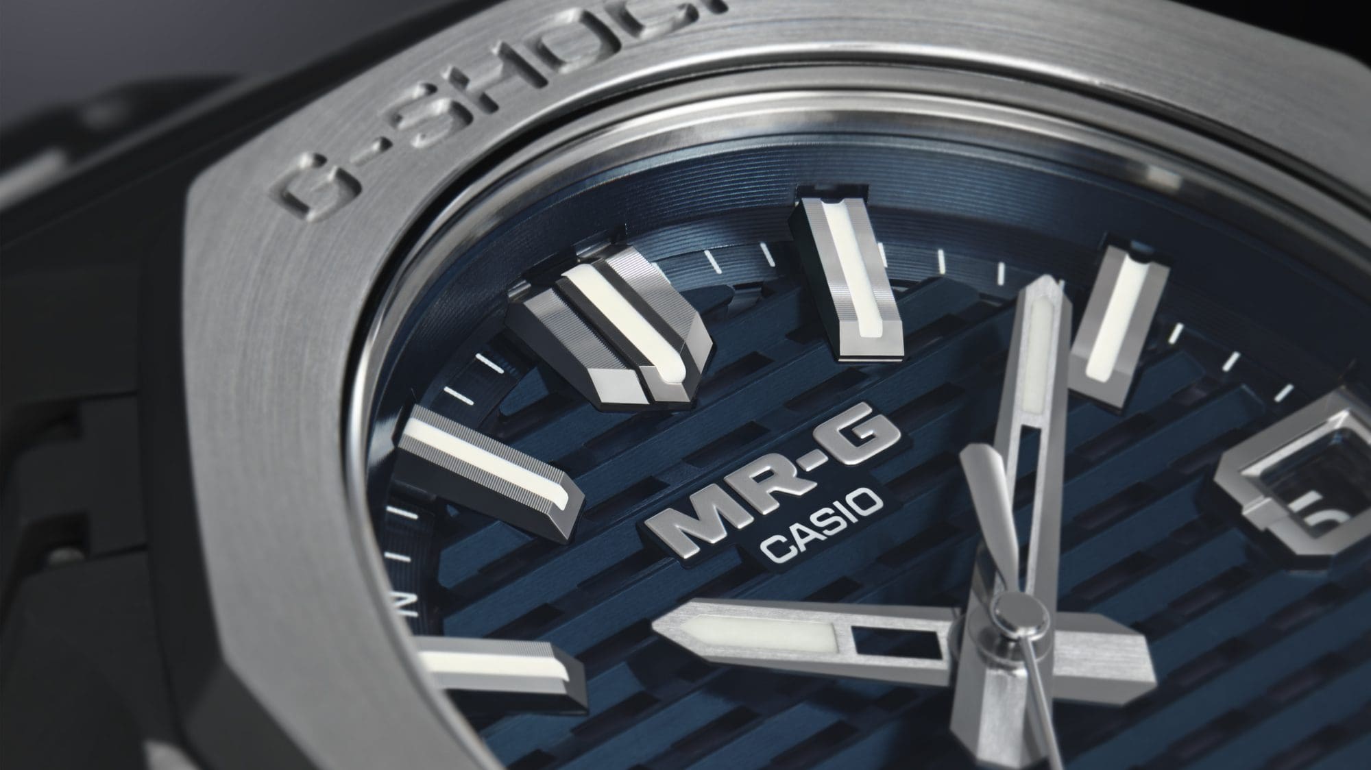 Close-up do mostrador azul escuro do MRG-B2100D-2ADR, evidenciando o seu design em grelha.