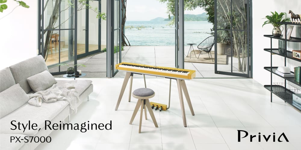 Uma sala de estar luminosa com grandes janelas francesas com vista para o mar, no centro da sala está um piano digital Privia PX-S7000HM com banco de piano a condizer. O texto complementa a imagem: “Style, Reimagined - PX-S7000 - Privia”. A página liga à página de informações do PX-S7000/PX-S6000.