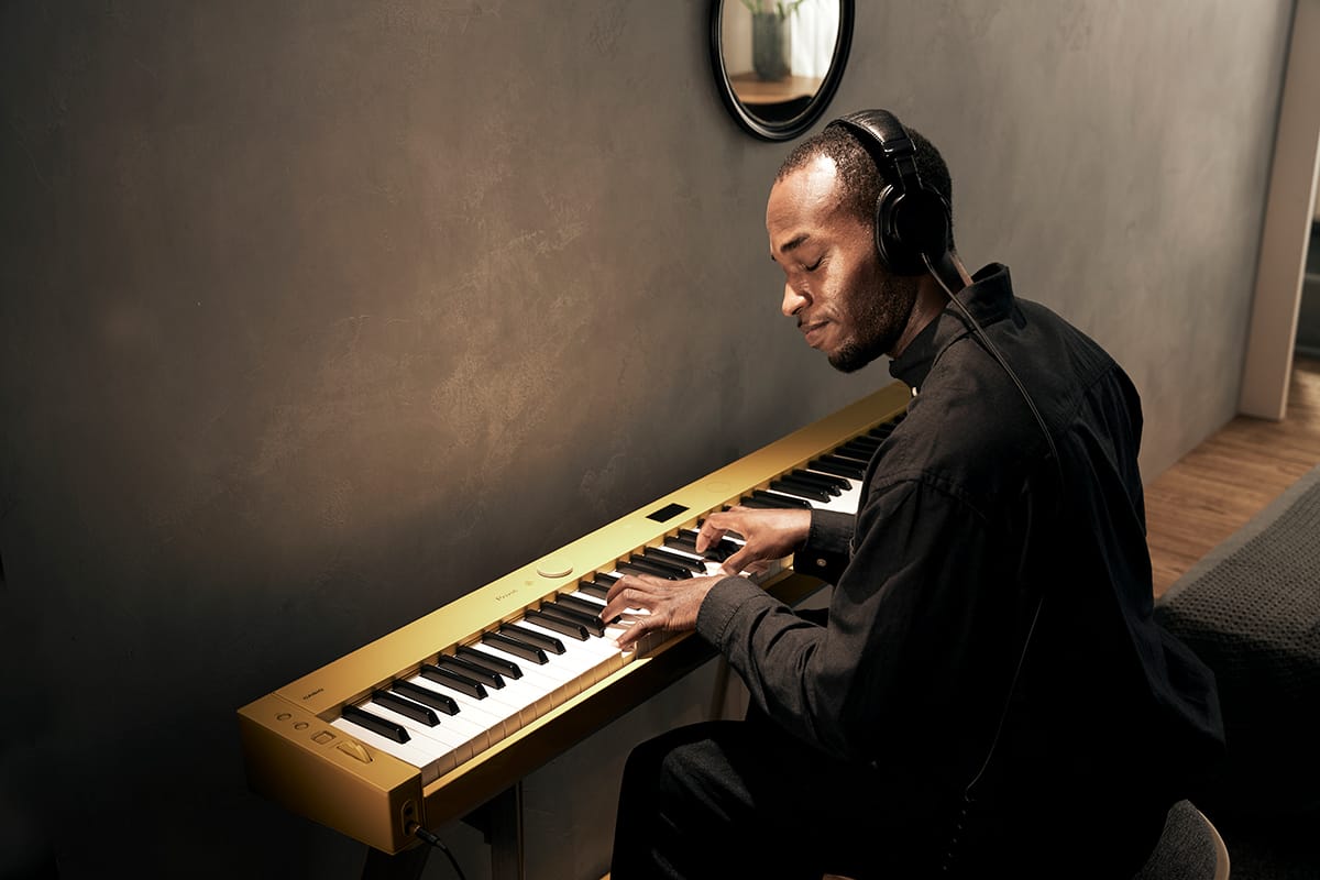 Um homem usa auscultadores e concentra-se em tocar o piano digital Privia PX-S7000HM